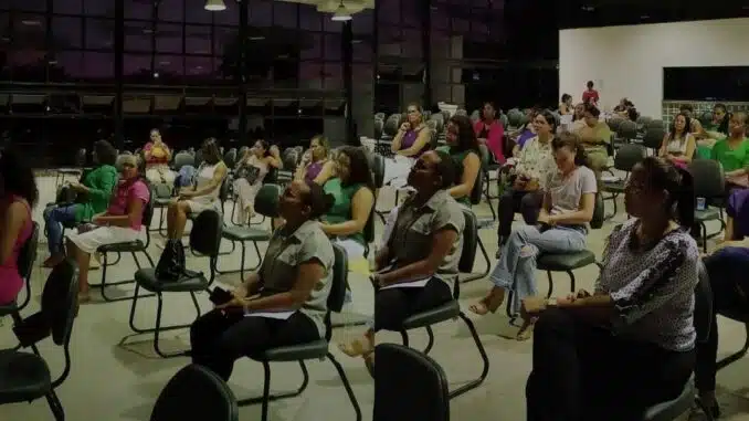 um grupo de mulheres sentadas em cadeiras observa alguém falar à sua frente